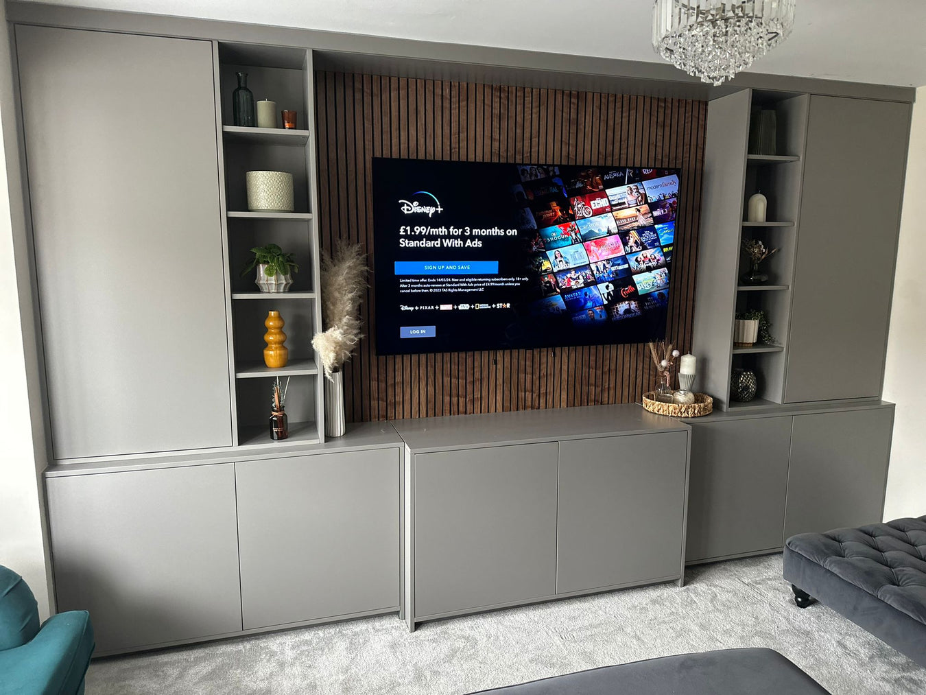 Front view of a media wall featuring timber walnut faced slat wall panels, enhancing the warm and modern aesthetic of the space.