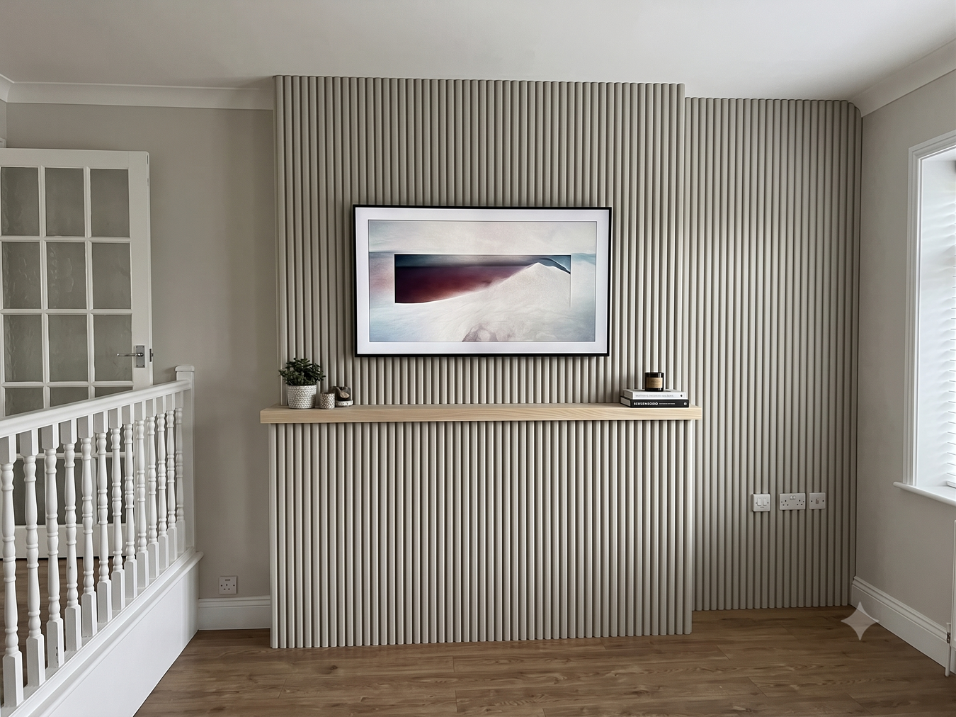 Front view of a media wall featuring timber walnut faced slat wall panels, enhancing the warm and modern aesthetic of the space.